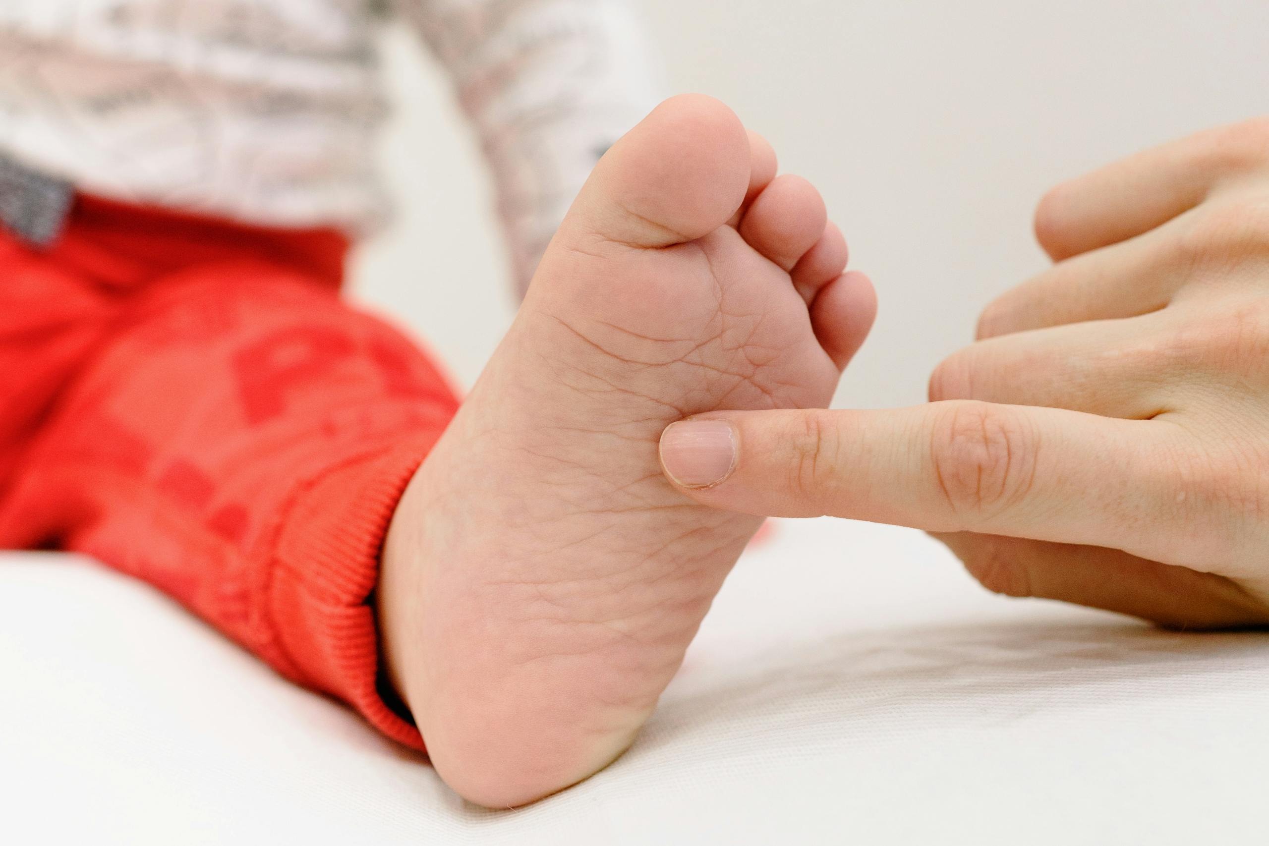 A touching moment between a baby's foot and an adult's finger, symbolizing care and connection.