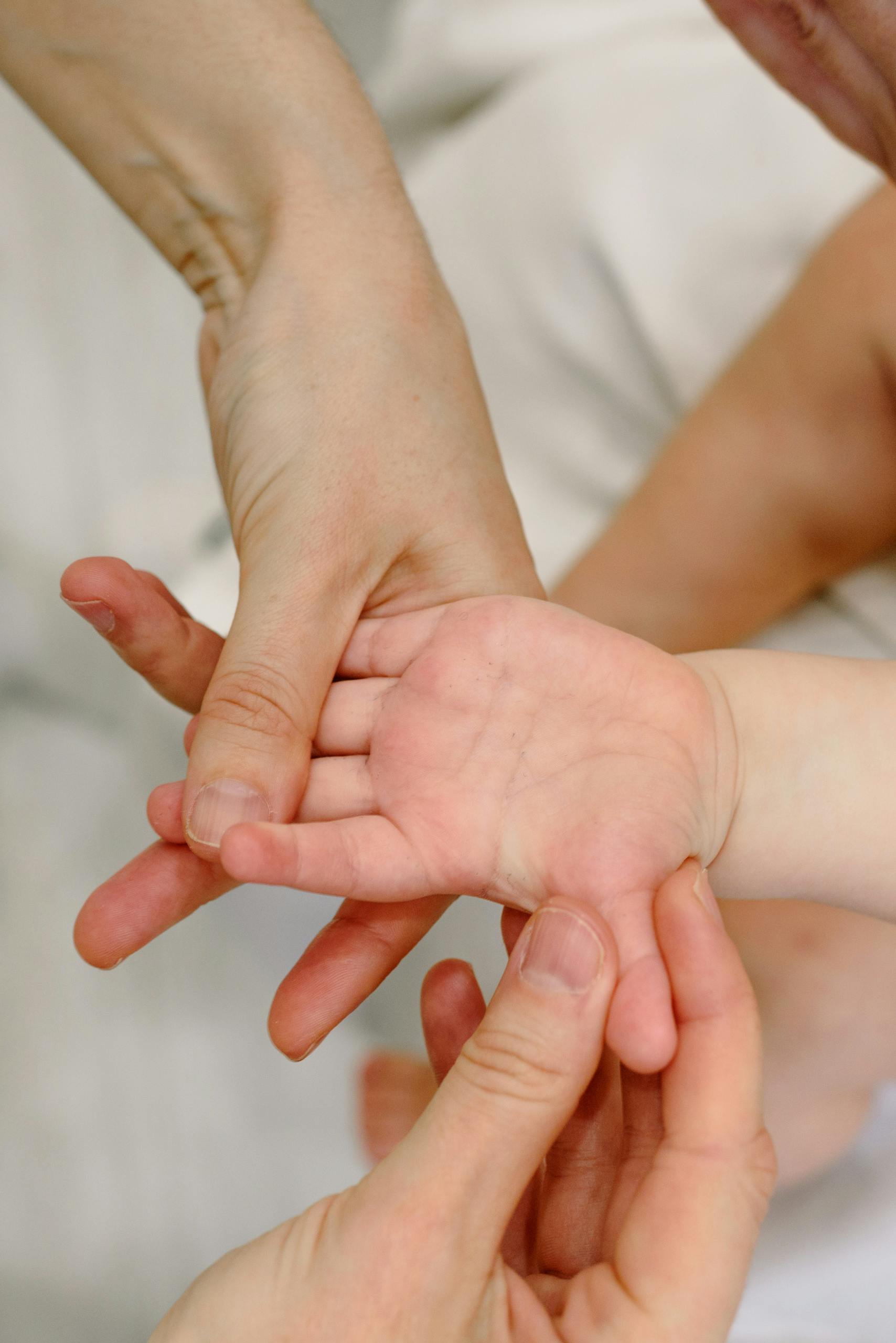 Close-up of adult and baby hands in a soothing massage setting, symbolizing care and connection.